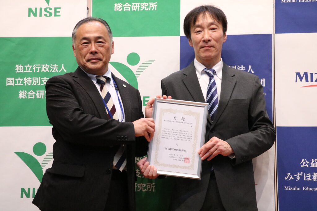 助成贈呈式で助成目録を手にする青木隆一特総研理事長（左）と松永量夫みずほ教育福祉財団常務理事（右）